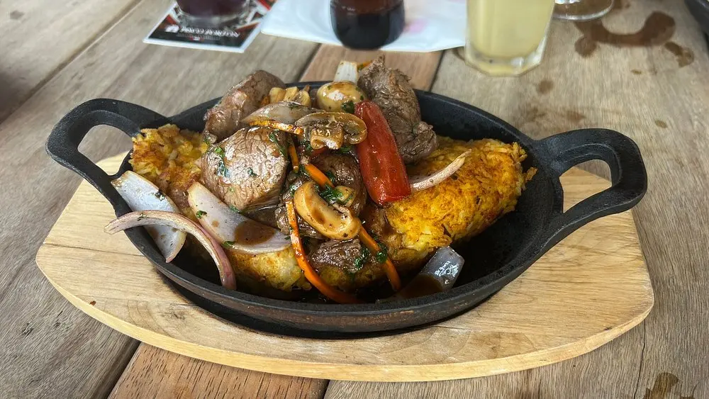 Plato gourmet de Lomo Saltado estilo Caravedo servido con papas rústicas y vegetales frescos.