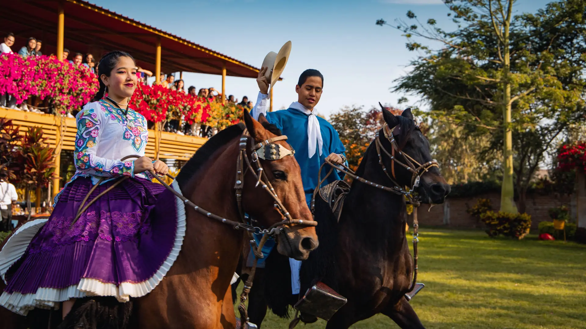 Chalanes montando elegantes caballos peruanos de paso en el patio principal de la hacienda colonial.