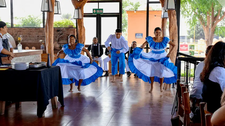 Bailarines con trajes típicos realizando una danza tradicional peruana durante un almuerzo campestre.